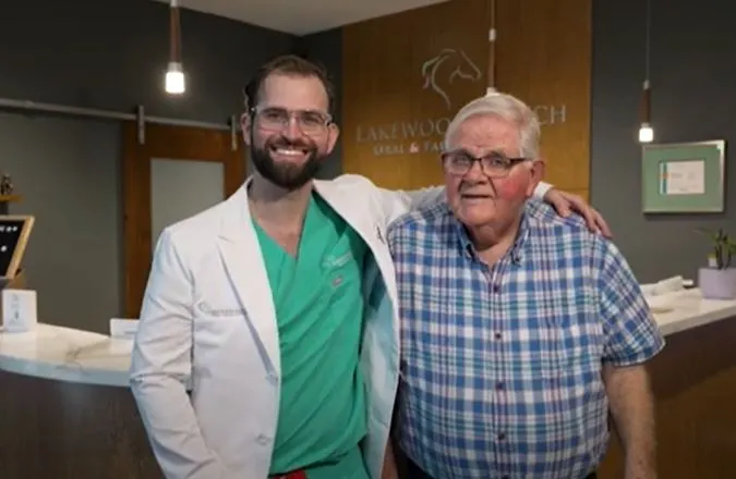 Dr. Austin L. Lyman with arm around older male patient in plaid shirt at reception area
