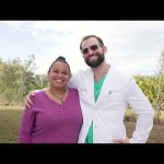 Dr. Austin Lyman in white coat posing with smiling female patient outdoors