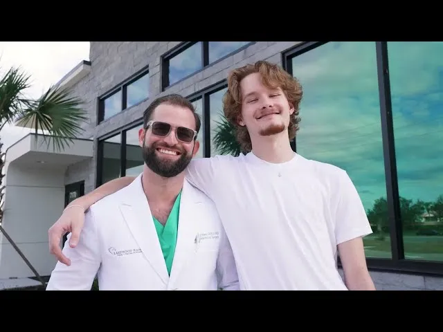Dr. Austin L. Lyman posing with young male patient outside modern dental office building