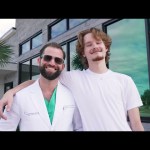 Dr. Austin L. Lyman posing with young male patient outside modern dental office building