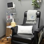 Comfortable black treatment chair with pillow, blanket, and medical monitoring equipment