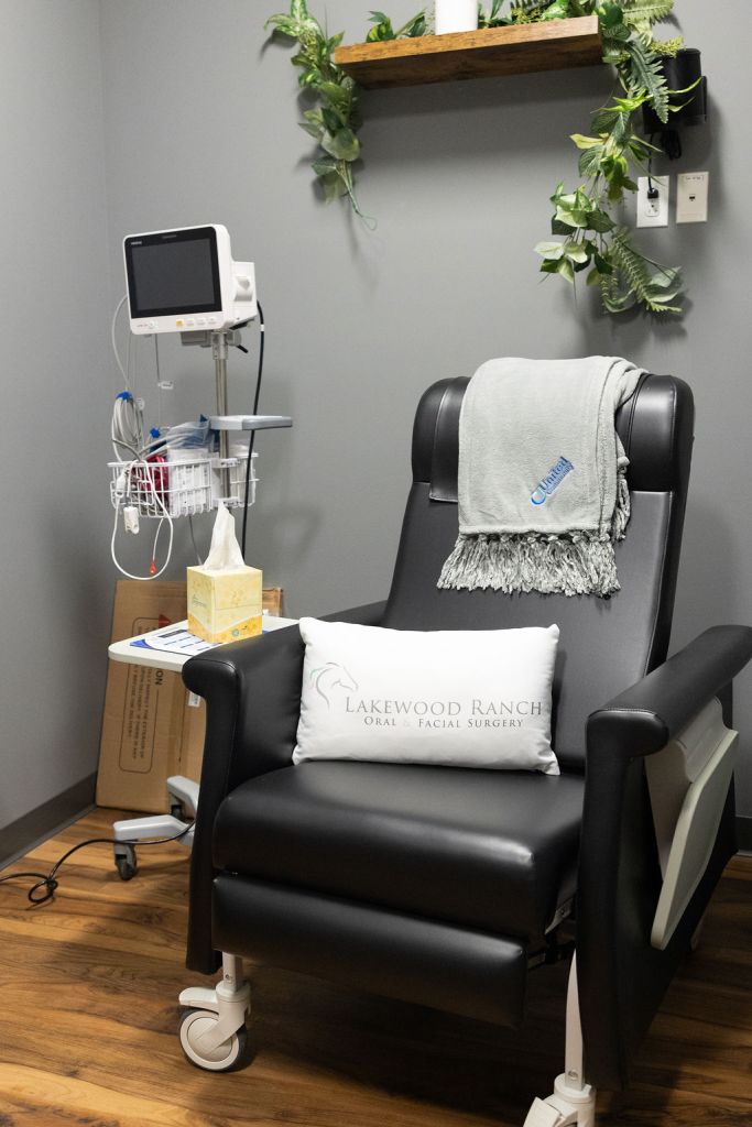 Comfortable black treatment chair with pillow, blanket, and medical monitoring equipment