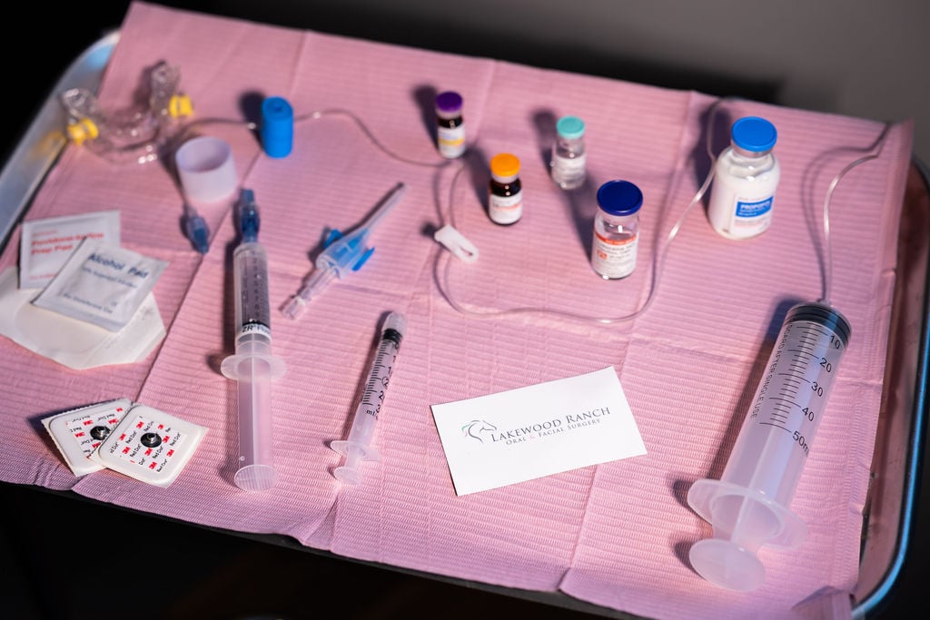 Sterile medical tray with syringes, medication vials, IV supplies, and anesthesia equipment